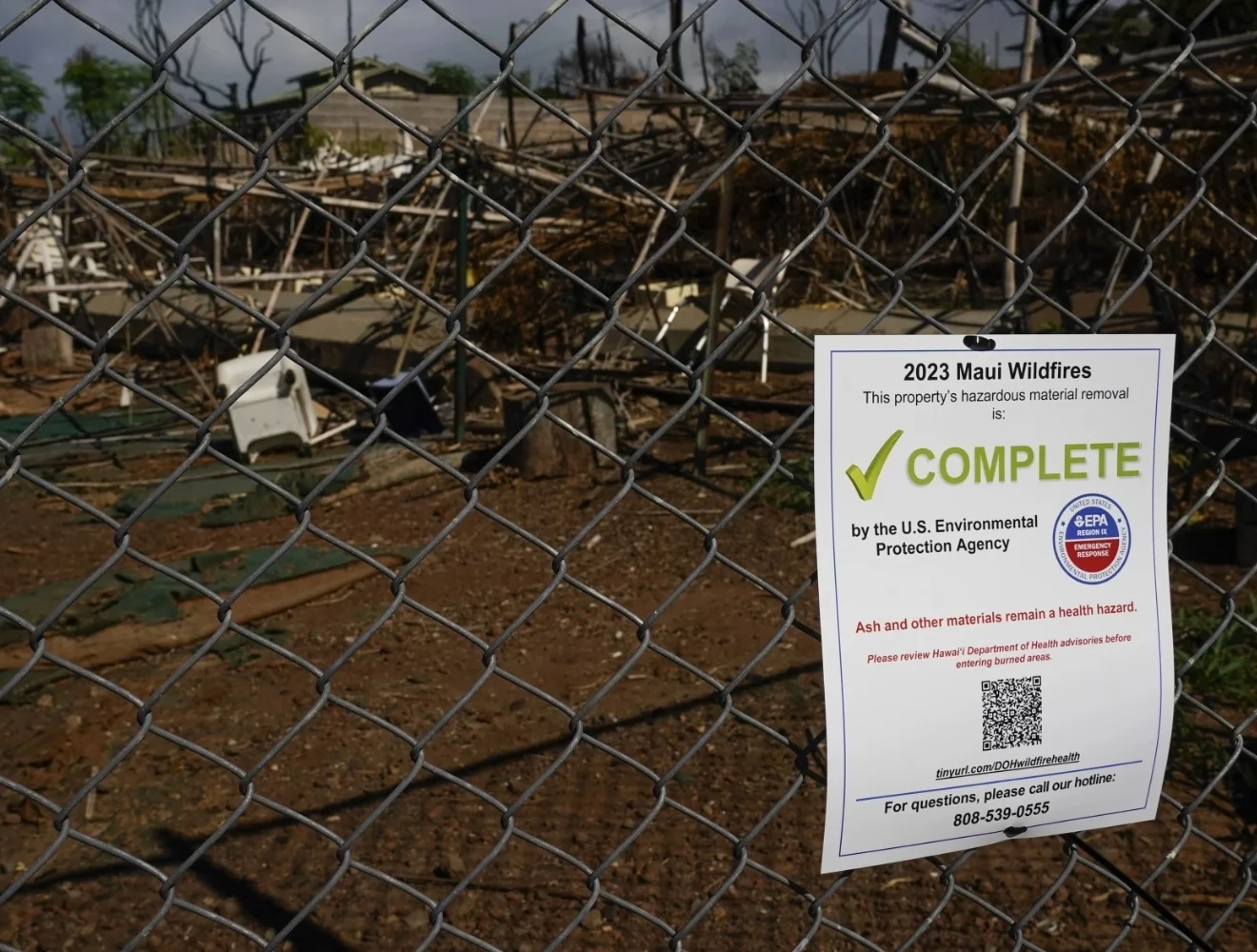 chain-link fence with rural background and a 2023 Maui Wildfires sign