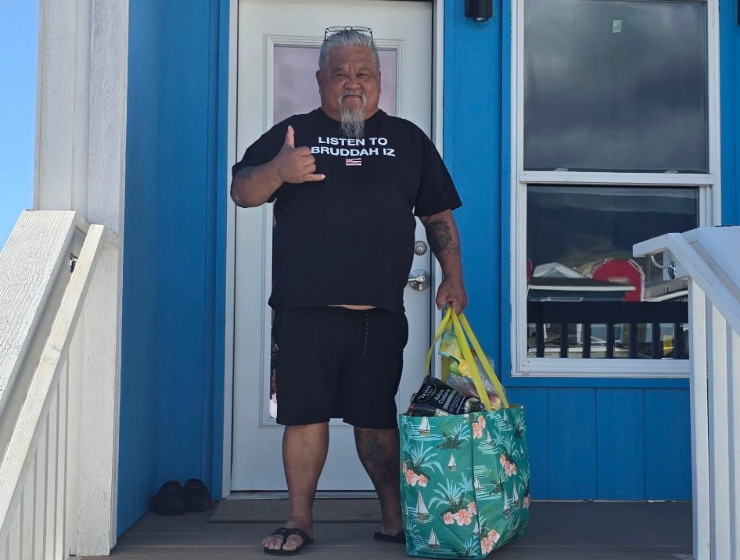 man making a shaka and holding a grocery bag